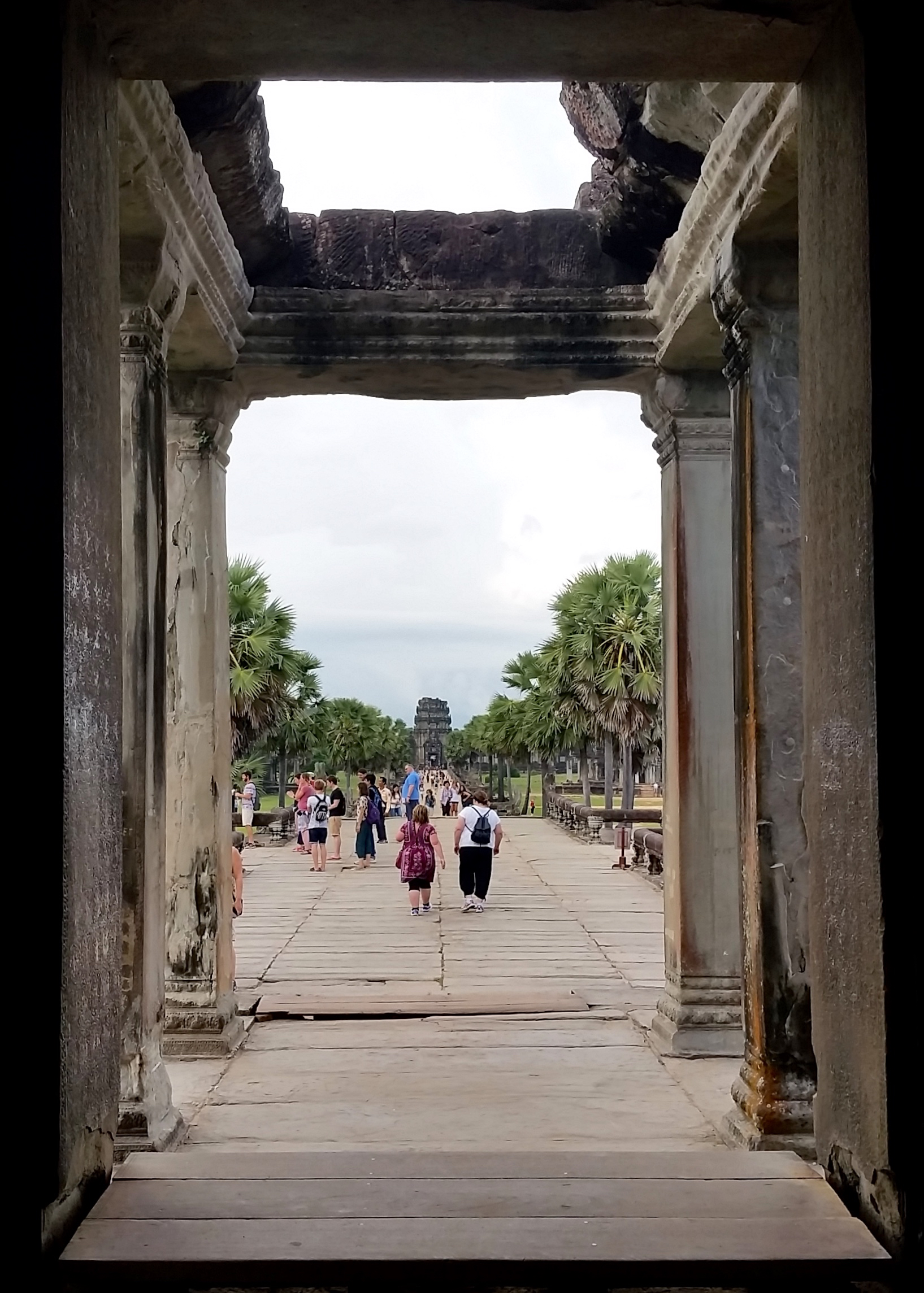 Fellow tourists make their way out of the enormous Angkor Wat temple in Siem Reap, tired from climbing many stairs and admiring many embossed pictures.